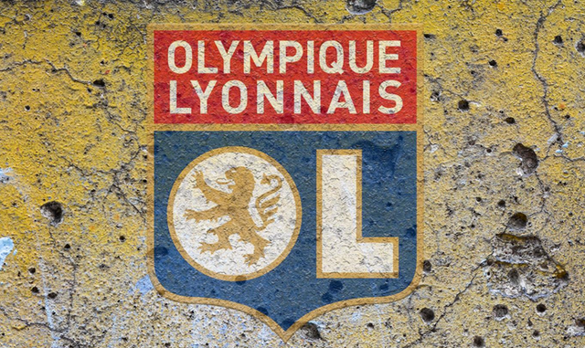 Logo de l'Olympique Lyonnais sur un mur criblé de trous et de lézardes.